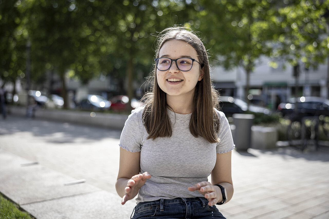 Eine junge Frau gestikuliert mit den Händen.