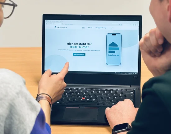 Zwei Personen sitzen vor einem Laptop und schauen sich die Internetseite zum lokal-o-mat an.