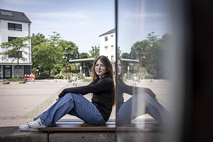 Eine junge Frau sitzt auf einer Mauer.