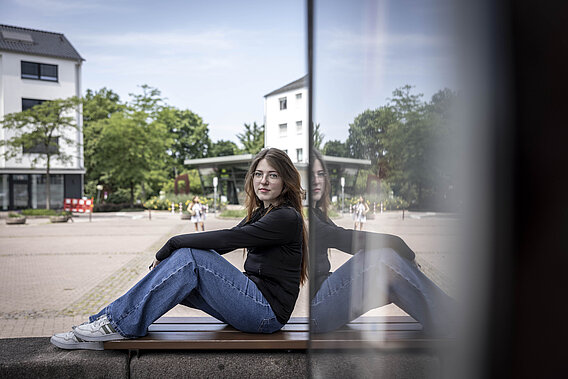 Eine junge Frau sitzt auf einer Mauer.