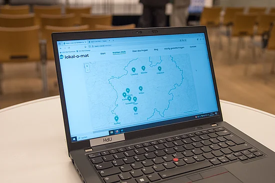 Auf dem Bildschirm eines Laptops ist eine Karte von Nordrhein-Westfalen abgebildet. 