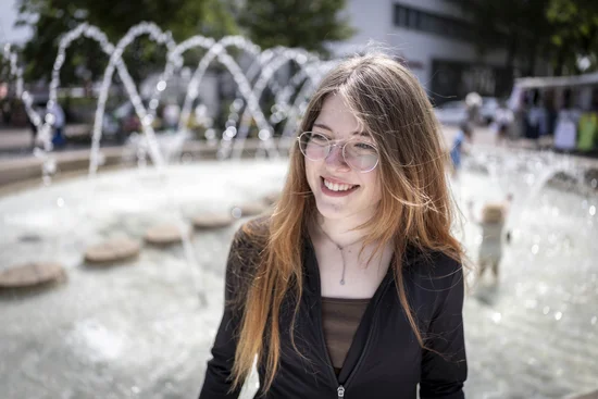 Eine junge Frau sitzt auf dem Rand eines Brunnens.