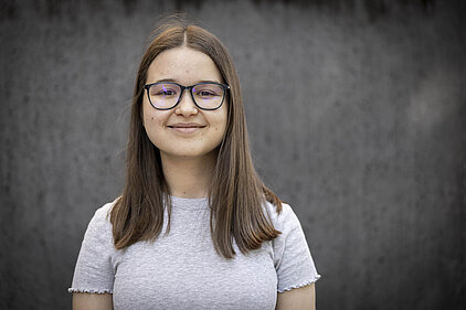 Eine junge Frau blickt in die Kamera.