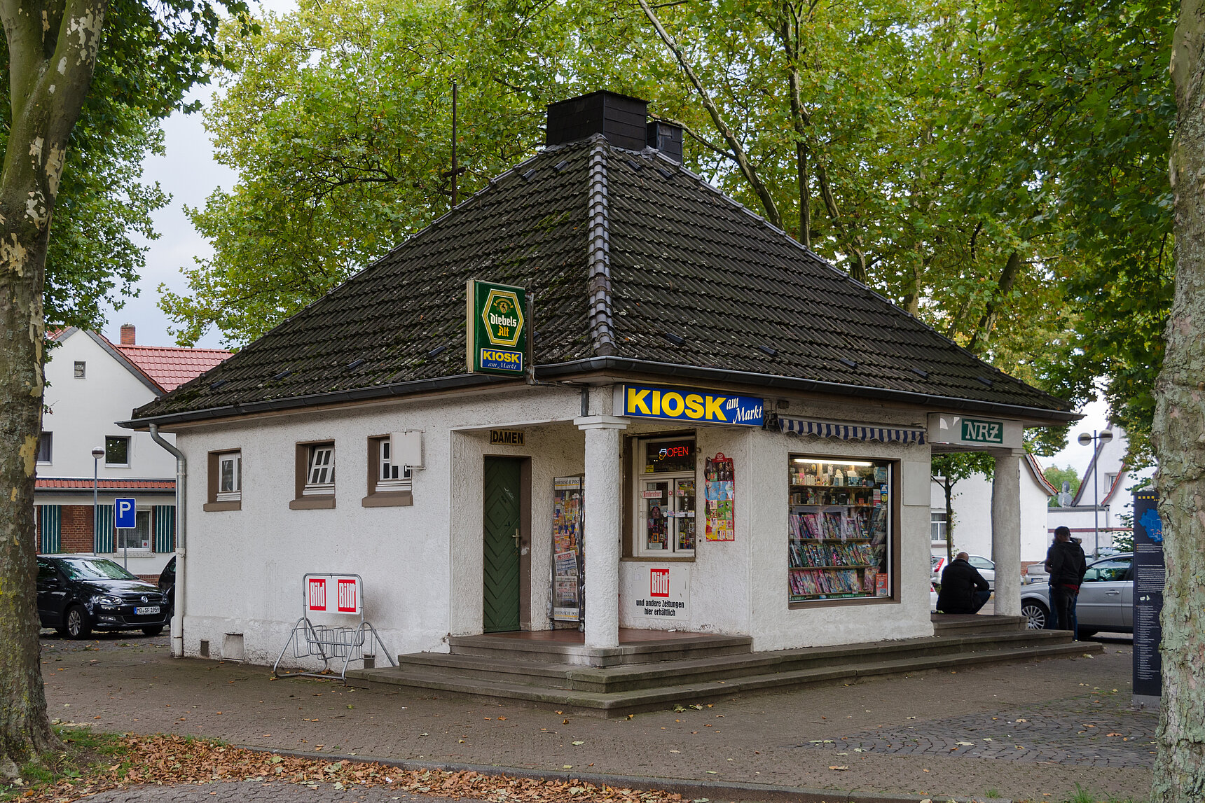 Ein kleines quadratisches Gebäude mit einer Leuchtreklame auf der Kiosk steht.